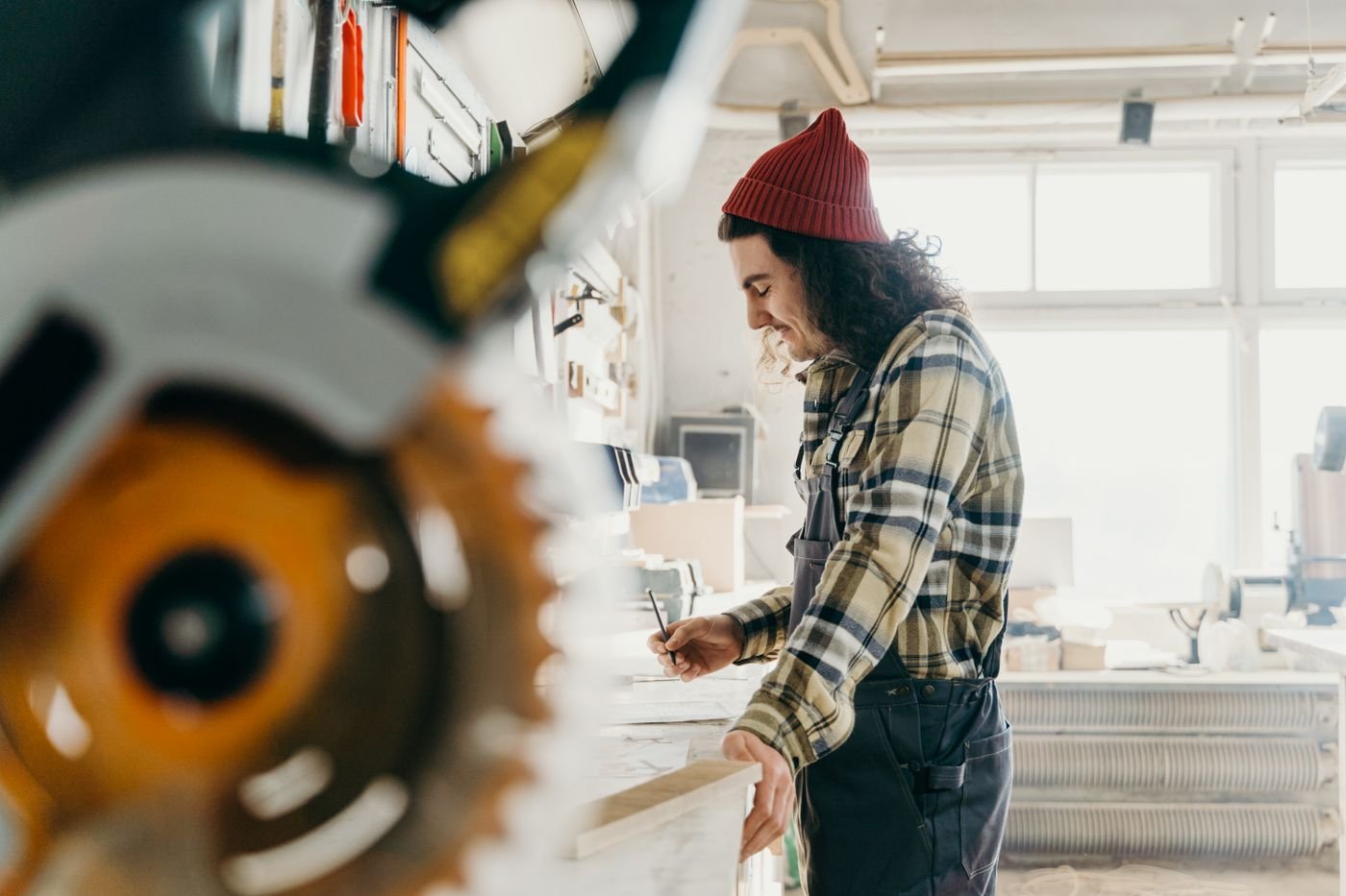 Artisan prenant les mesures d’une pièce de bois dans son atelier