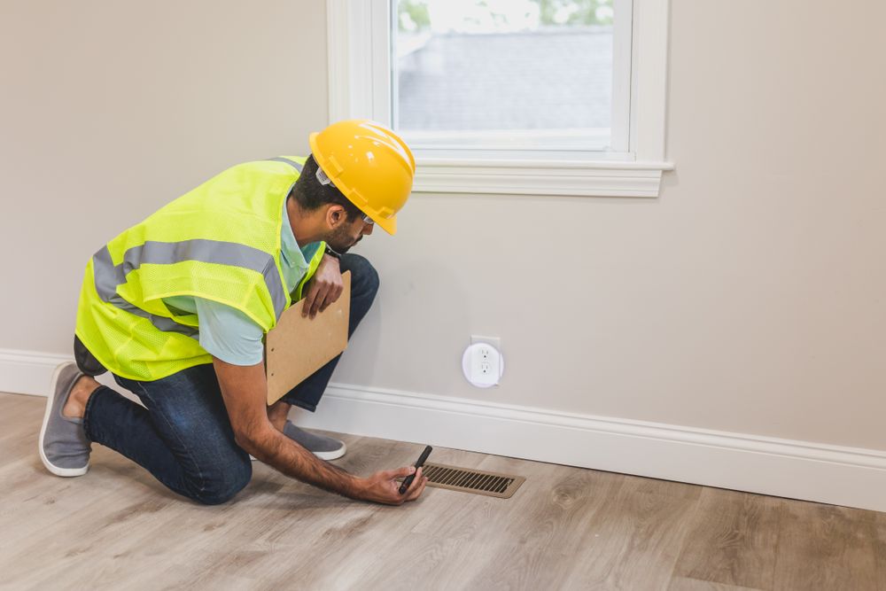 Technicien contrôlant une grille de ventilation